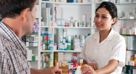 Female pharmacist handing medication over to a man