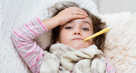 Young girl in a dressing gown with a thermometer in her mouth looking unwell